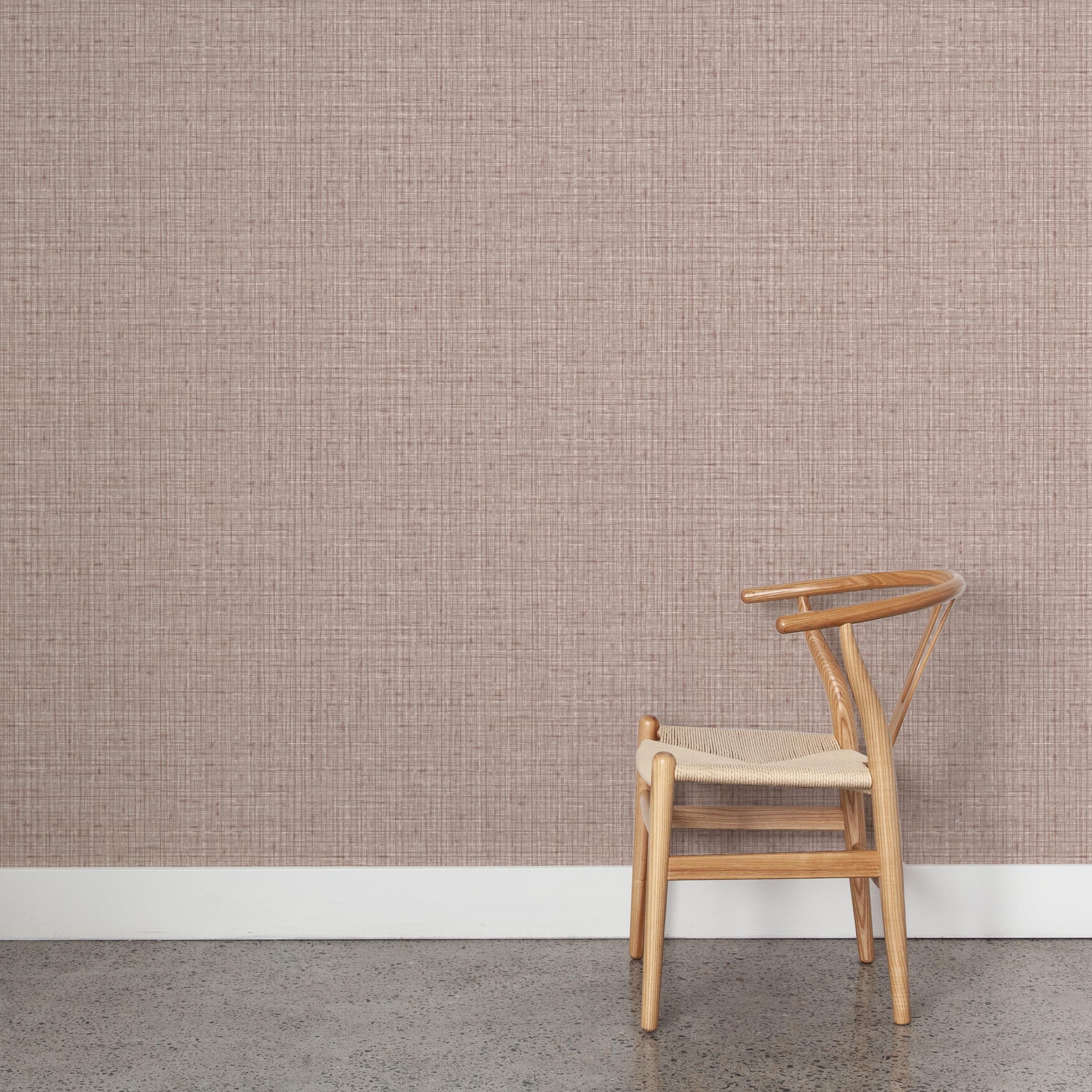 A wooden chair stands in front of a wall papered in a textured tweed pattern in shades of purple.