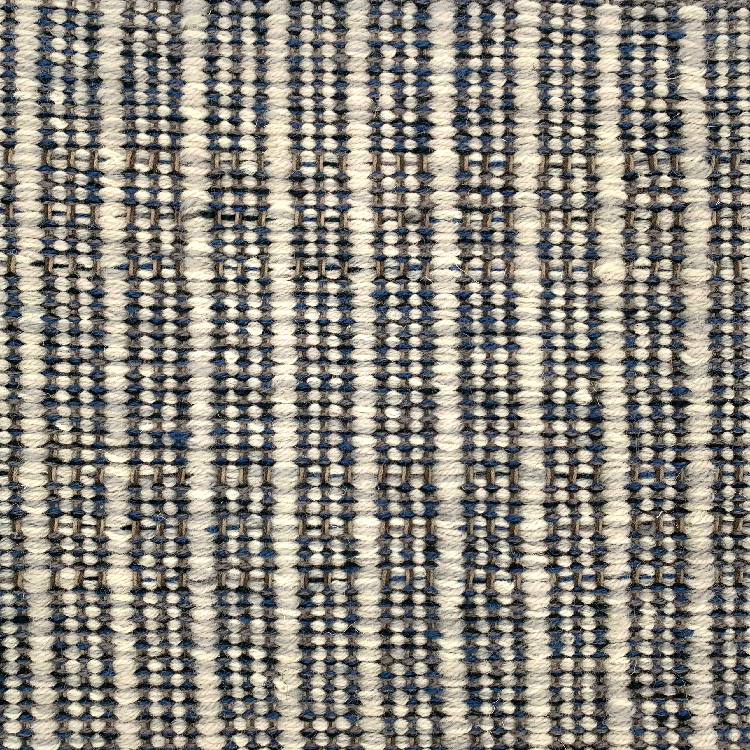 Handwoven rug detail in a stripe design in black and white