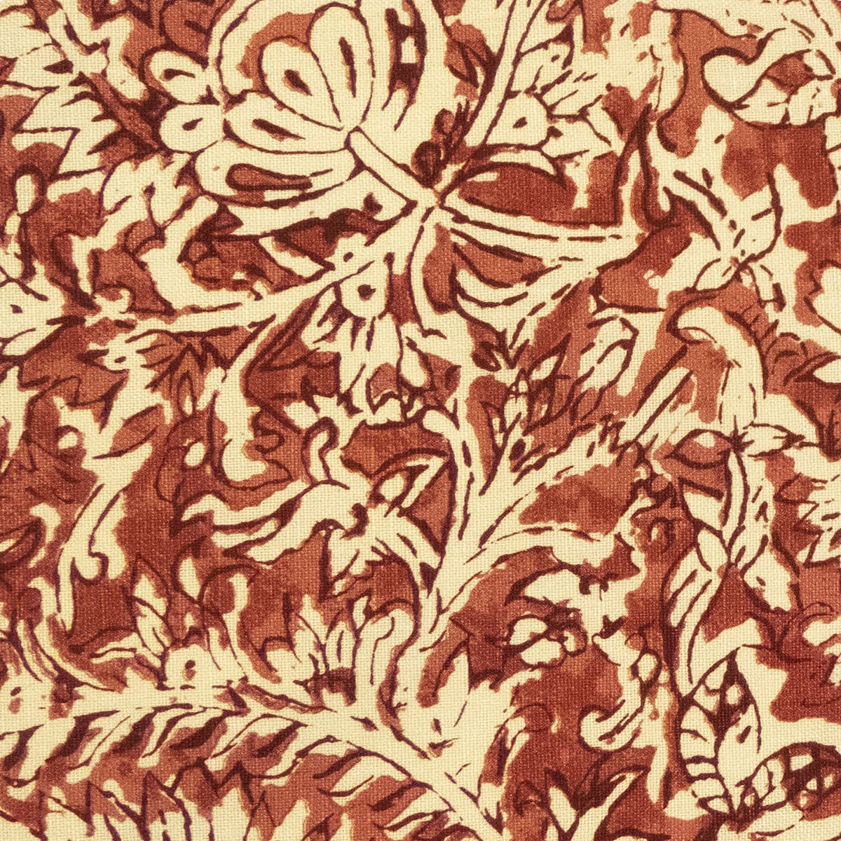 Detail of fabric in a floral paisley print shades of red and brown on a tan field.