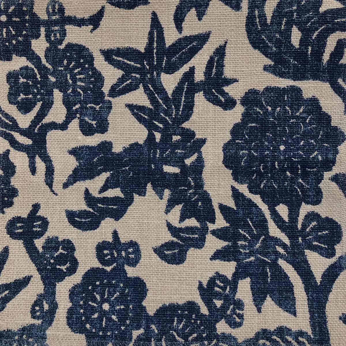 Detail of fabric in a minimalist floral print in indigo on a light brown field.