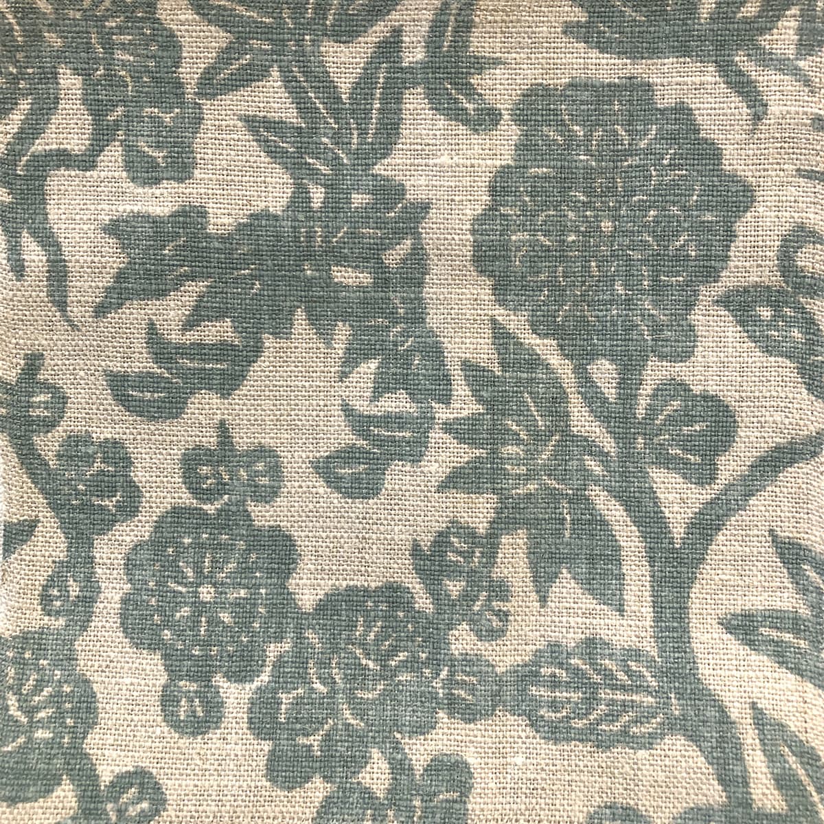 Detail of fabric in a minimalist floral print in teal on a light brown field.