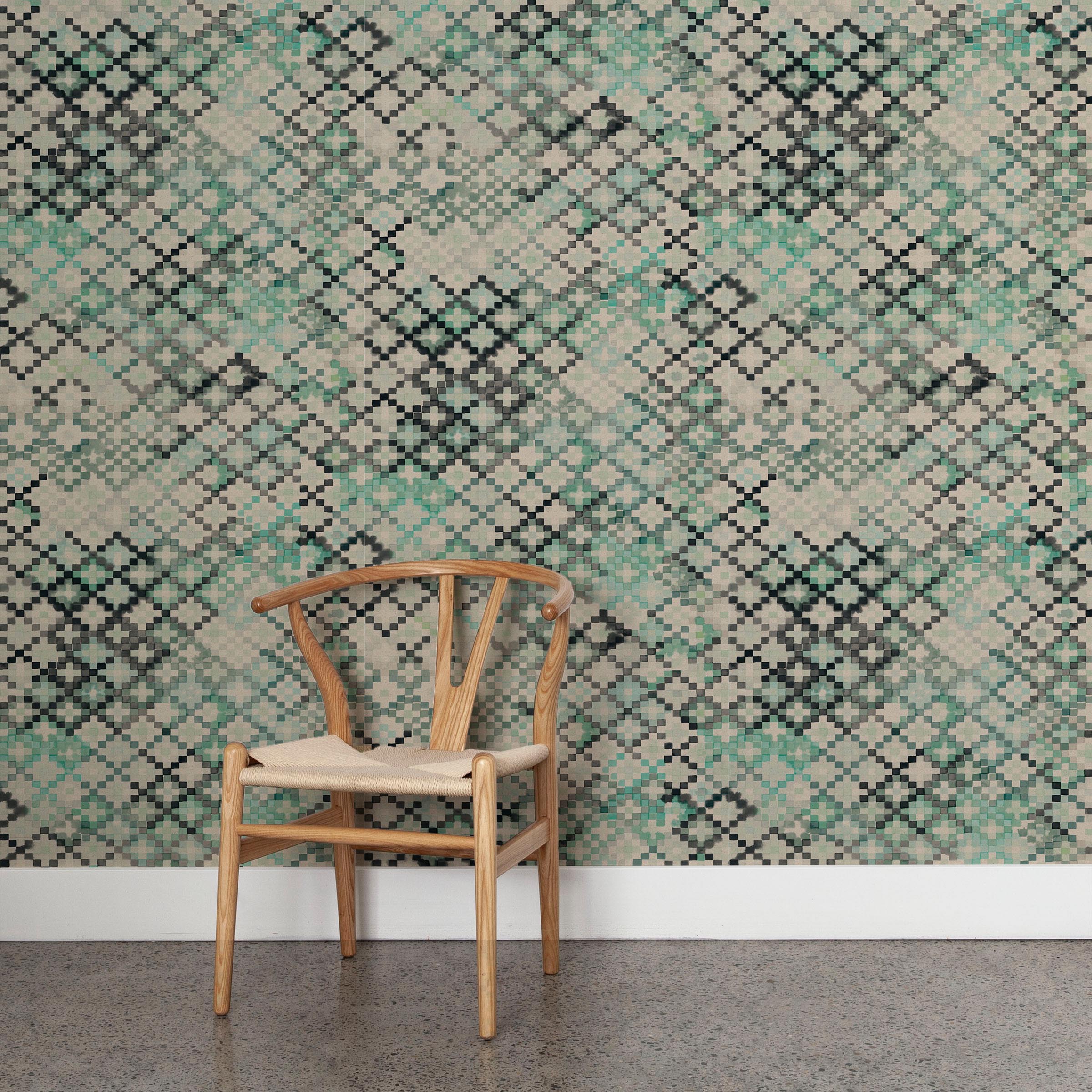 A wooden chair stands in front of a wall papered in a diamond checked pattern in shades of cream, gray and green.