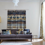 A living room with a hanging textile and throw pillows in the same abstract paint swatch print.