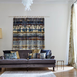 A living room with a hanging textile and throw pillows in the same abstract paint swatch print.