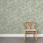 A wooden chair stands in front of a wall papered in a playful wave print in white on a sage watercolor field.