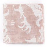 A stack of fabric swatches in a playful wave print in white on a light pink watercolor field.