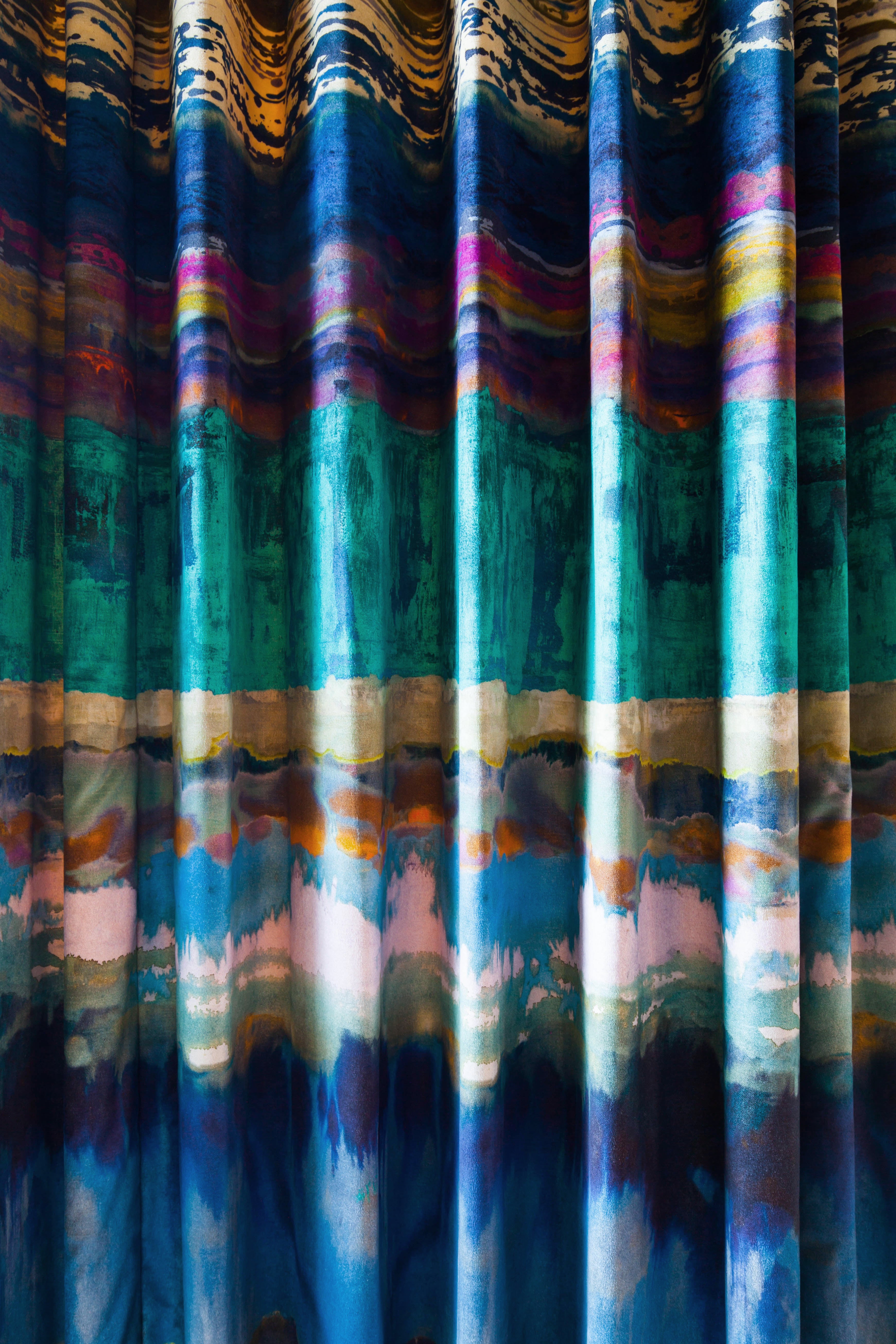 Draped fabric yardage in an abstract paint swatch print in shades of blue, turquoise and pink.