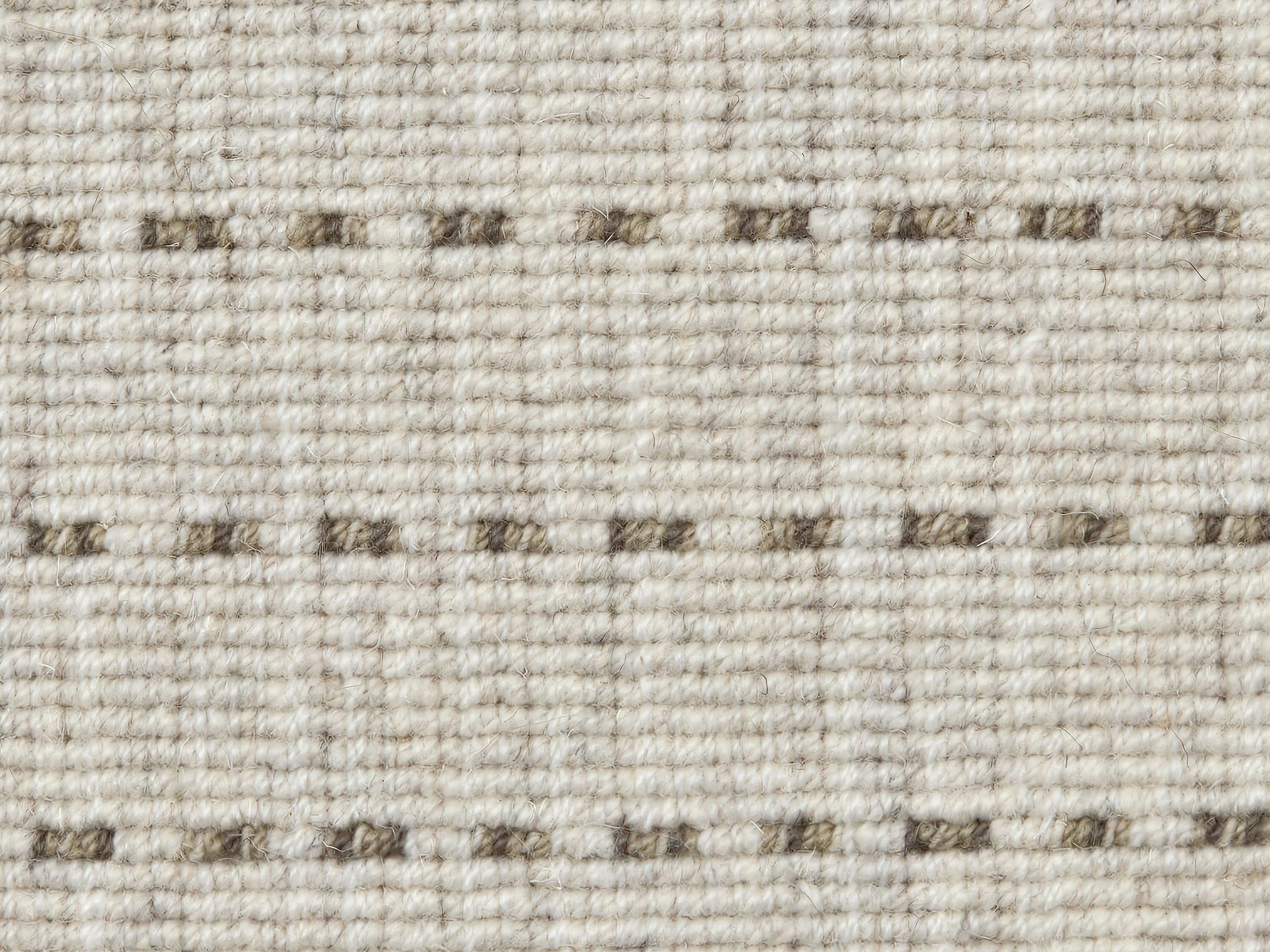 Broadloom carpet detail in a oatmeal field with a brown dotted stripe.