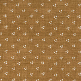 Detail of a linen fabric in a clustered dot pattern in cream on a camel field.