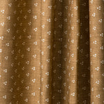 Draped printed fabric in a clustered dot pattern in cream on a camel field.