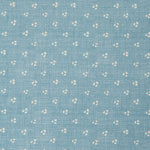 Detail of a linen fabric in a clustered dot pattern in cream on a sky blue field.