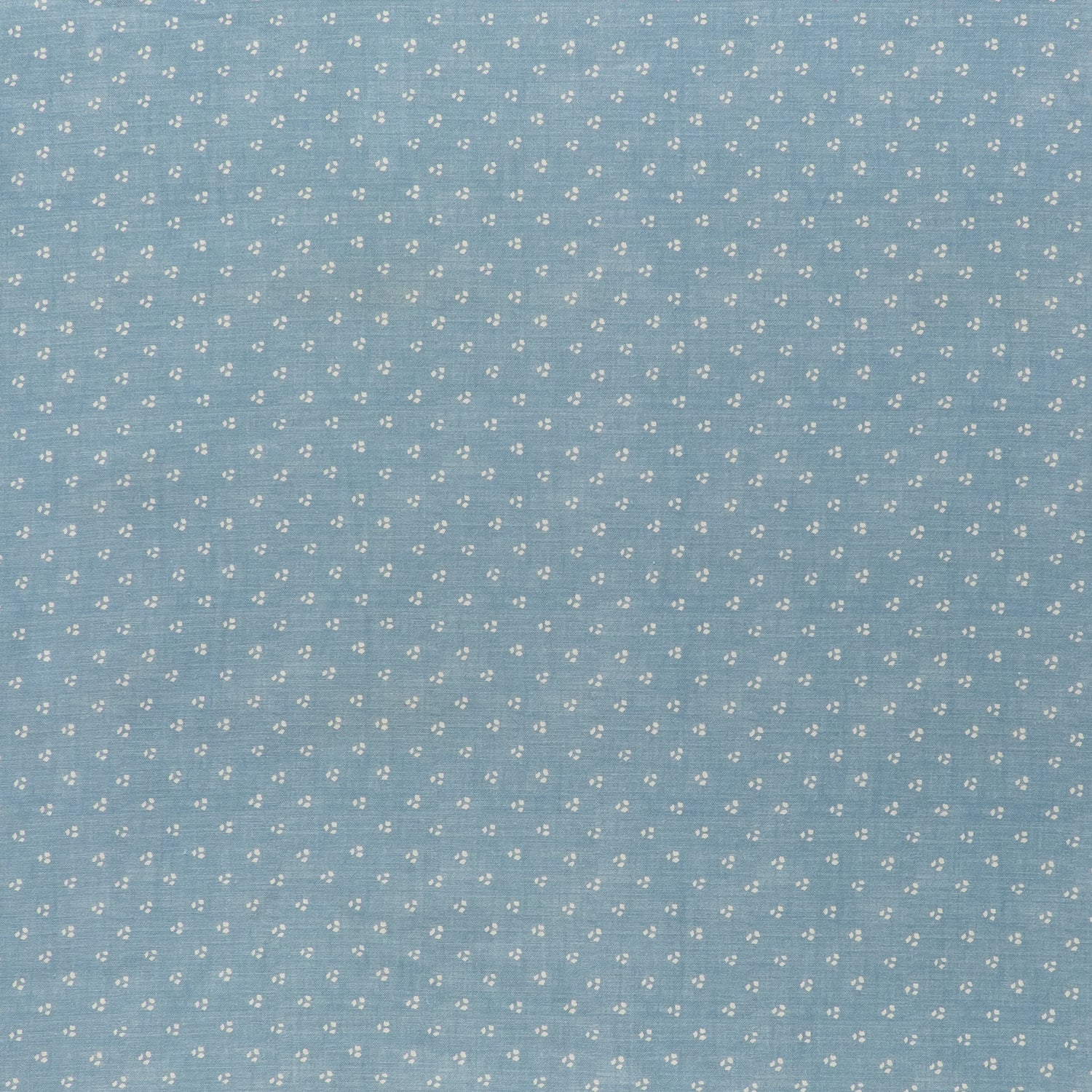 printed linen fabric in a clustered dot pattern in cream on a sky blue field.