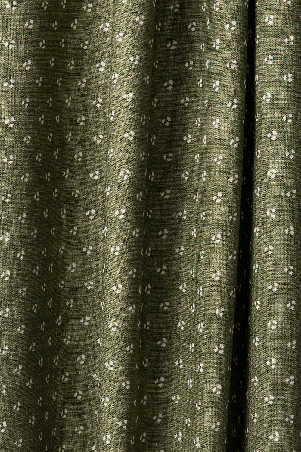 Draped printed fabric in a clustered dot pattern in cream on a moss field.