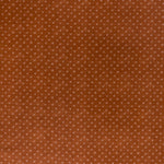 printed linen fabric in a clustered dot pattern in beige on a burnt orange field.