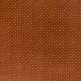 printed linen fabric in a clustered dot pattern in beige on a burnt orange field.