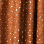 Draped printed fabric in a clustered dot pattern in beige on a burnt orange field.