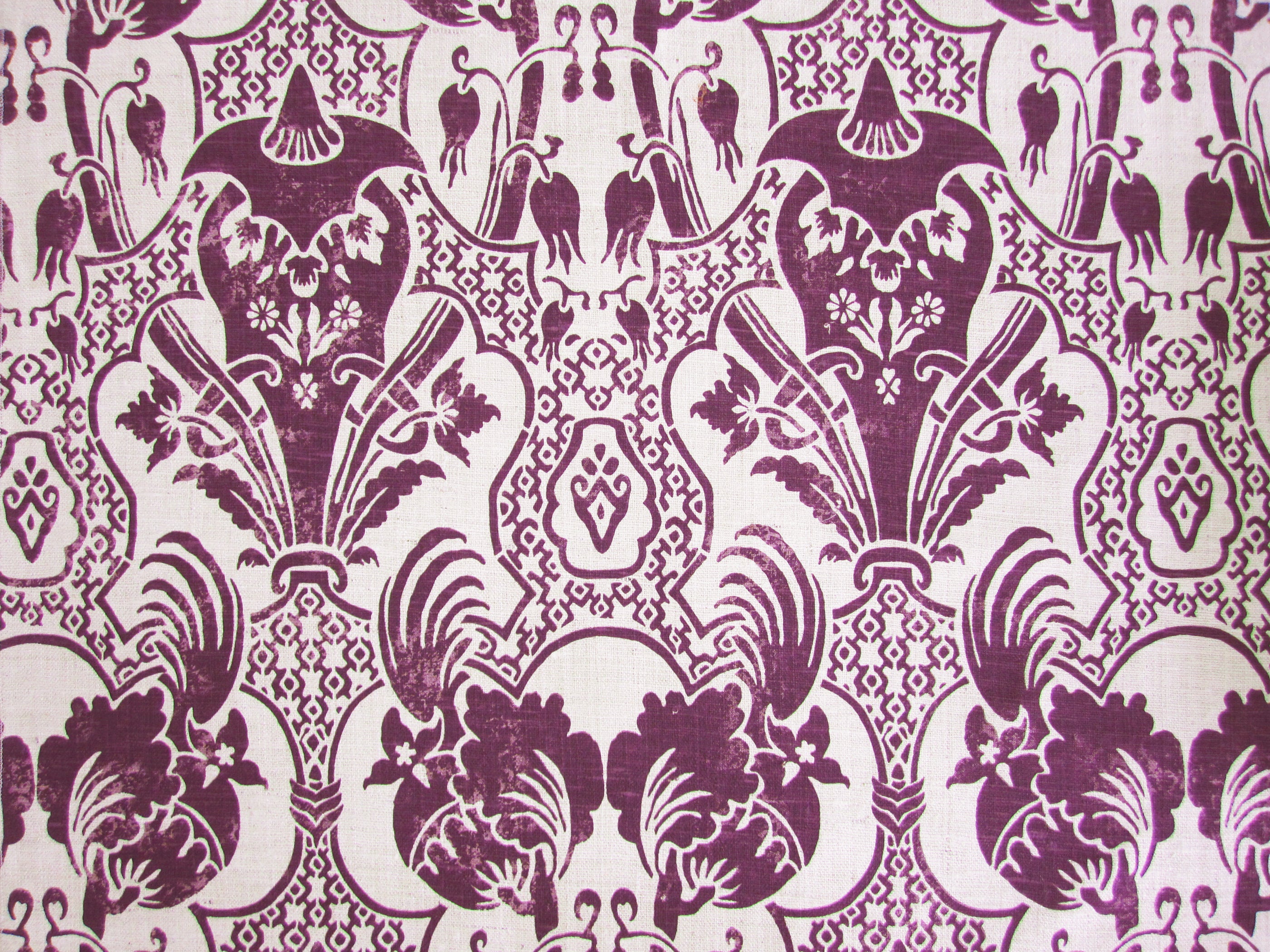 Detail of fabric in a damask vase print in purple on a cream field.