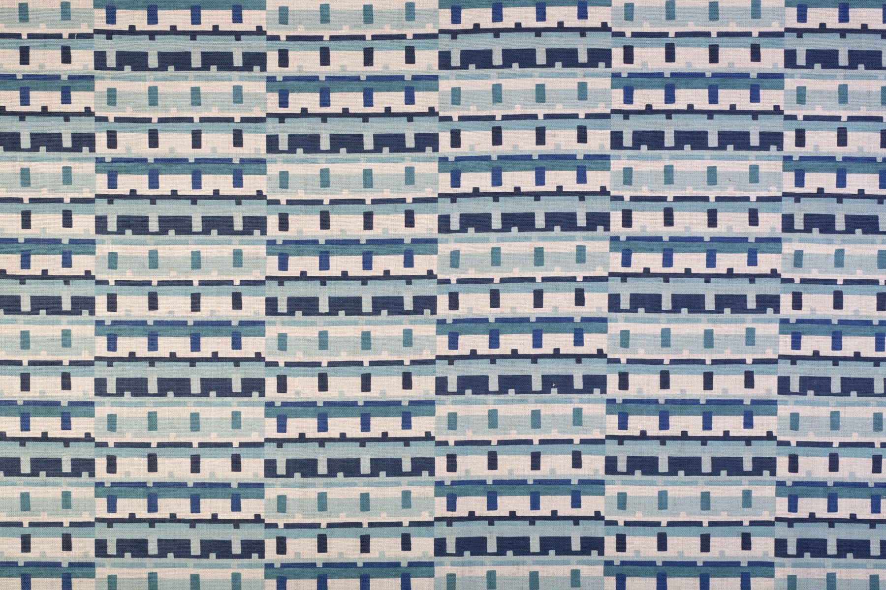 Detail of fabric in a playful geometric grid print in shades of blue, navy and white.