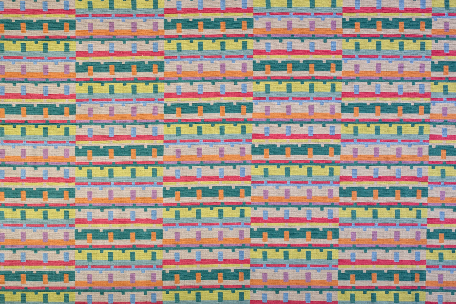 Detail of fabric in a playful geometric grid print in shades of pink, orange and green.