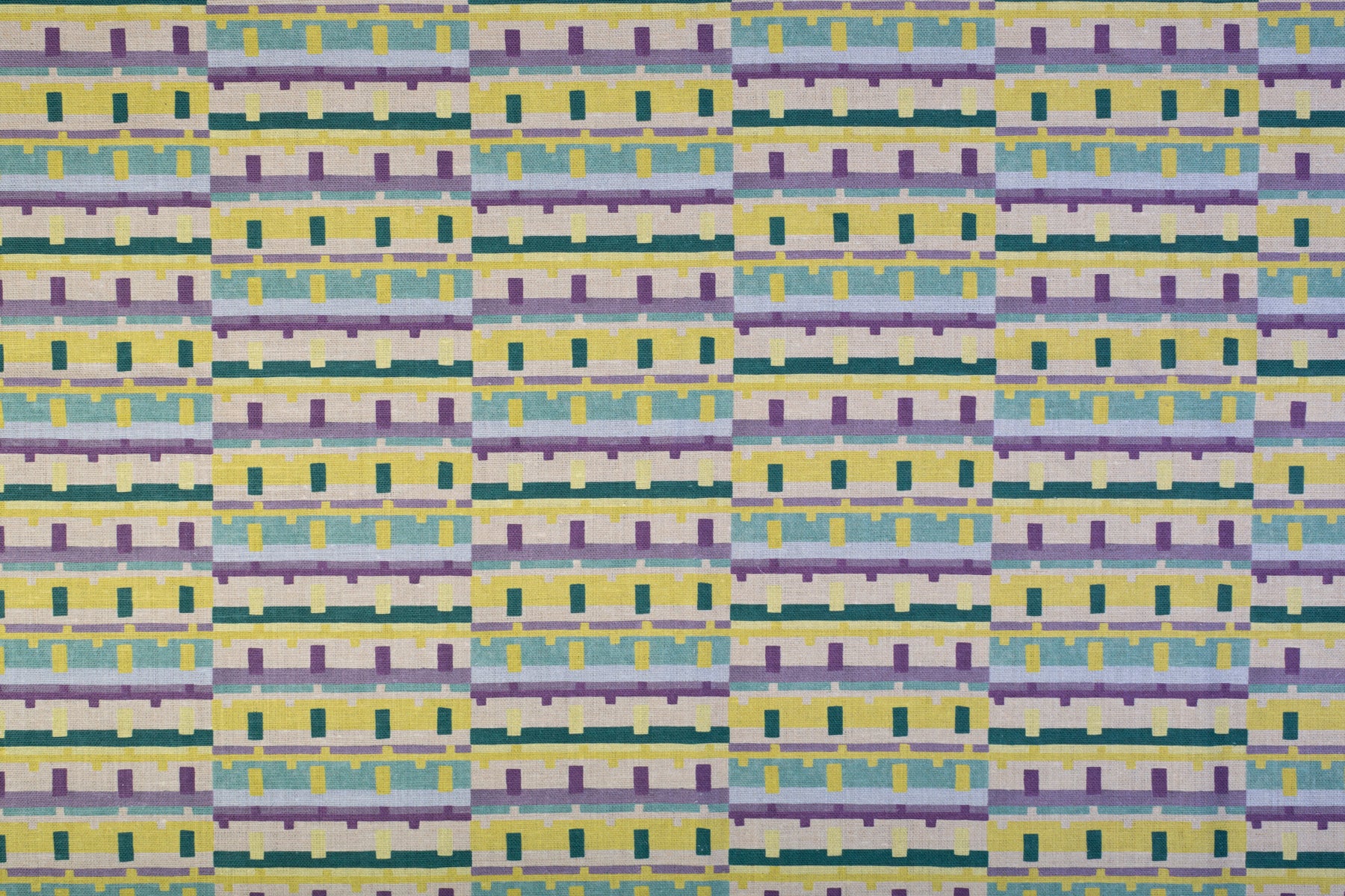 Detail of fabric in a playful geometric grid print in shades of purple, yellow and green.