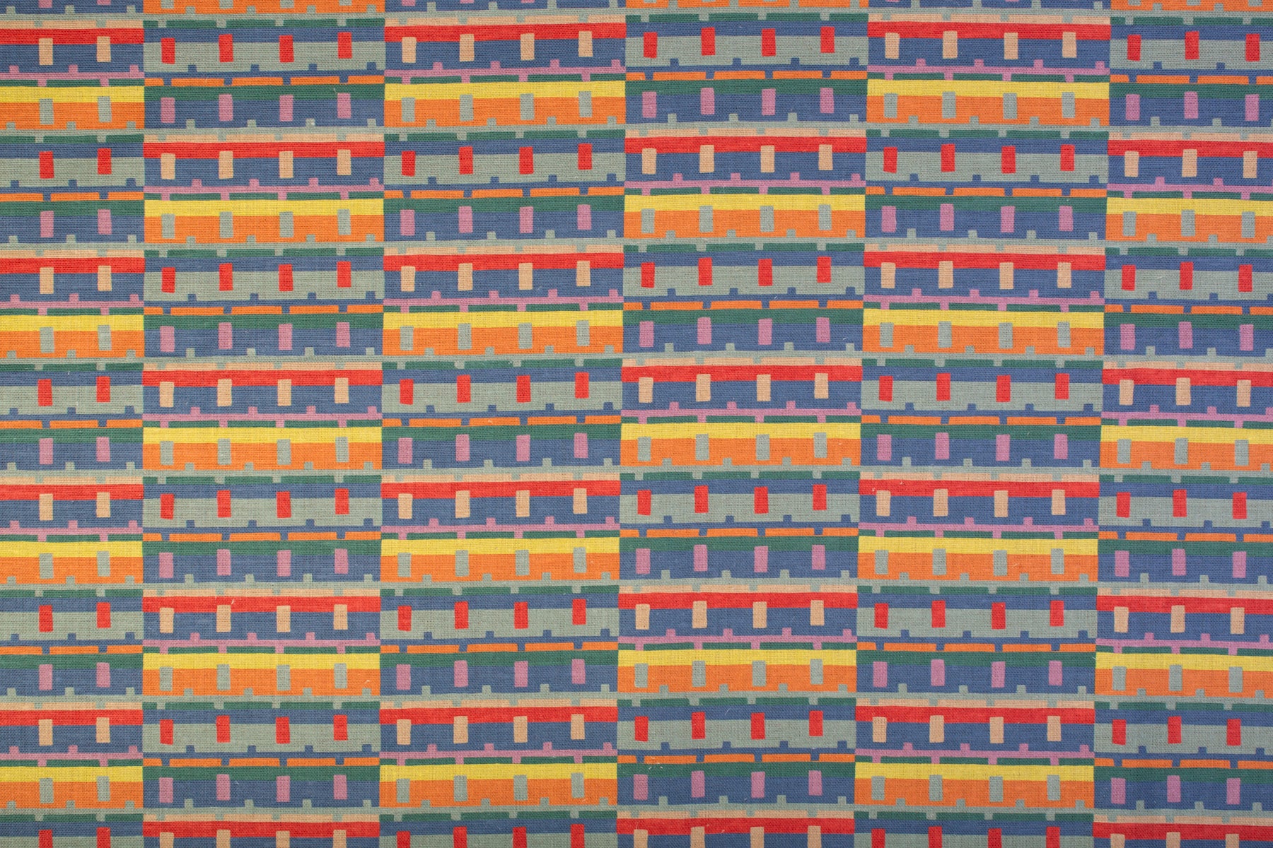 Detail of fabric in a playful geometric grid print in shades of purple, red, blue and orange.