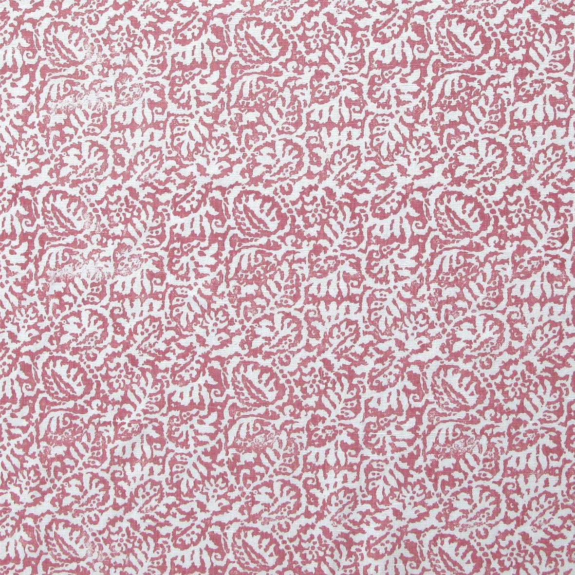 Detail of fabric in a dense paisley print in white on a pink field.