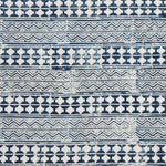 Detail of fabric in a dense geometric stripe in indigo on a white field.