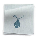 A stack of fabric swatches in a playful animal and branch print in navy on a blue field.