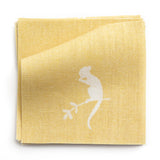 A stack of fabric swatches in a playful animal and branch print in white on a yellow field.