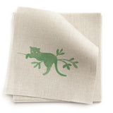 A stack of fabric swatches in a playful animal and branch print in green on a tan field.