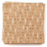A stack of fabric swatches in a small-scale dot and dash pattern in shades of cream and brown on a bronze field.