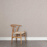 A wooden chair stands in front of a wall papered in a small-scale dot and dash pattern in white and gray on a cream field.