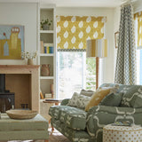 Detail of a living room with a couch upholstered in a leafy lattice print in cream on a hunter green field.