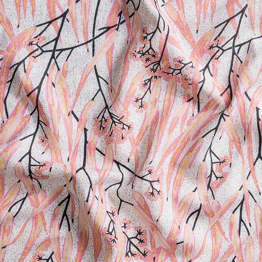Detail of a fabric with long thin leaves and berries in a palette of pink and yellow with black branches.