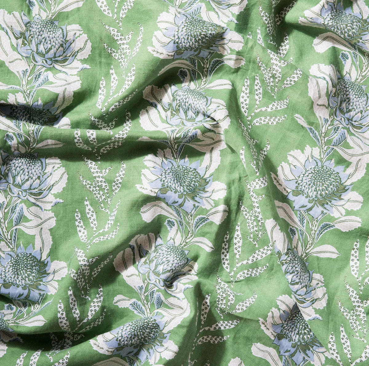 Draped fabric in a linear floral print in shades of cream and light blue on a green field.