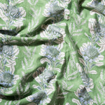 Draped fabric in a linear floral print in shades of cream and light blue on a green field.
