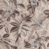 Draped fabric in a leaf and branch print in cream, brown and navy on a tan field.
