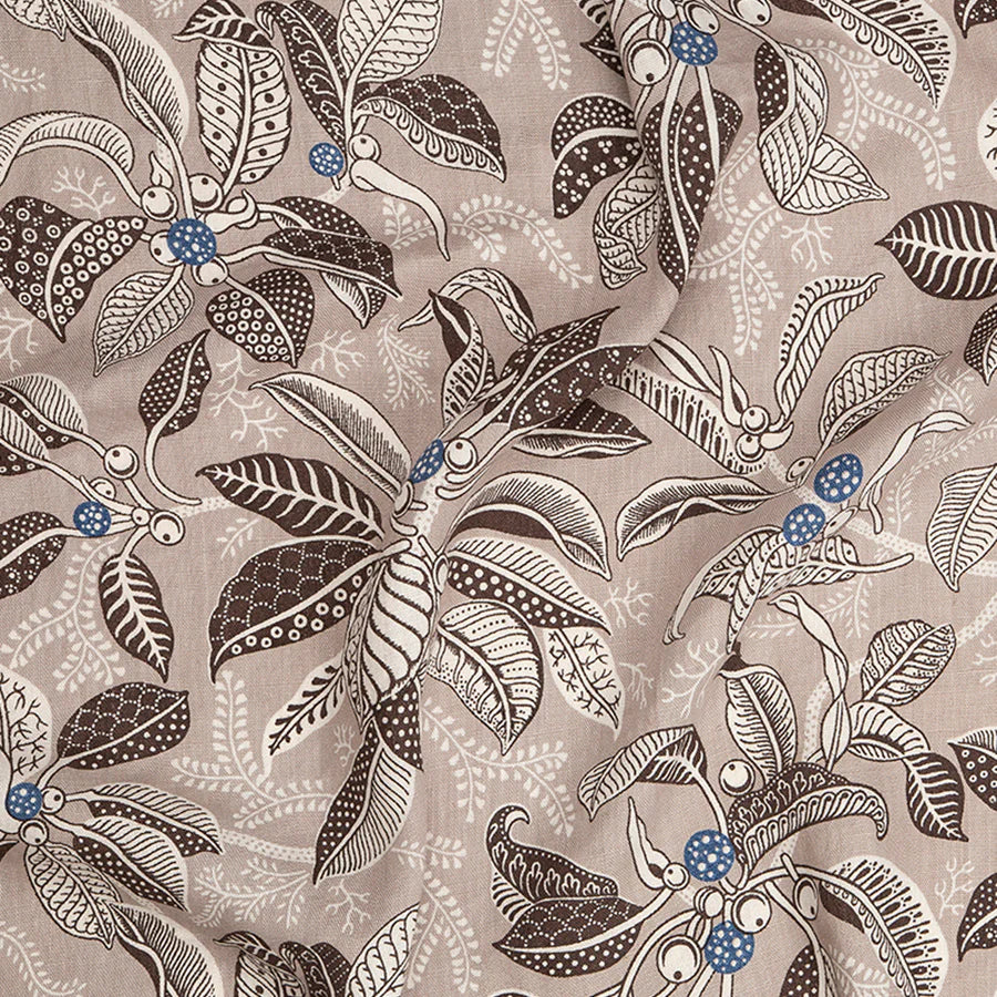 Draped fabric in a leaf and branch print in cream, brown and navy on a tan field.