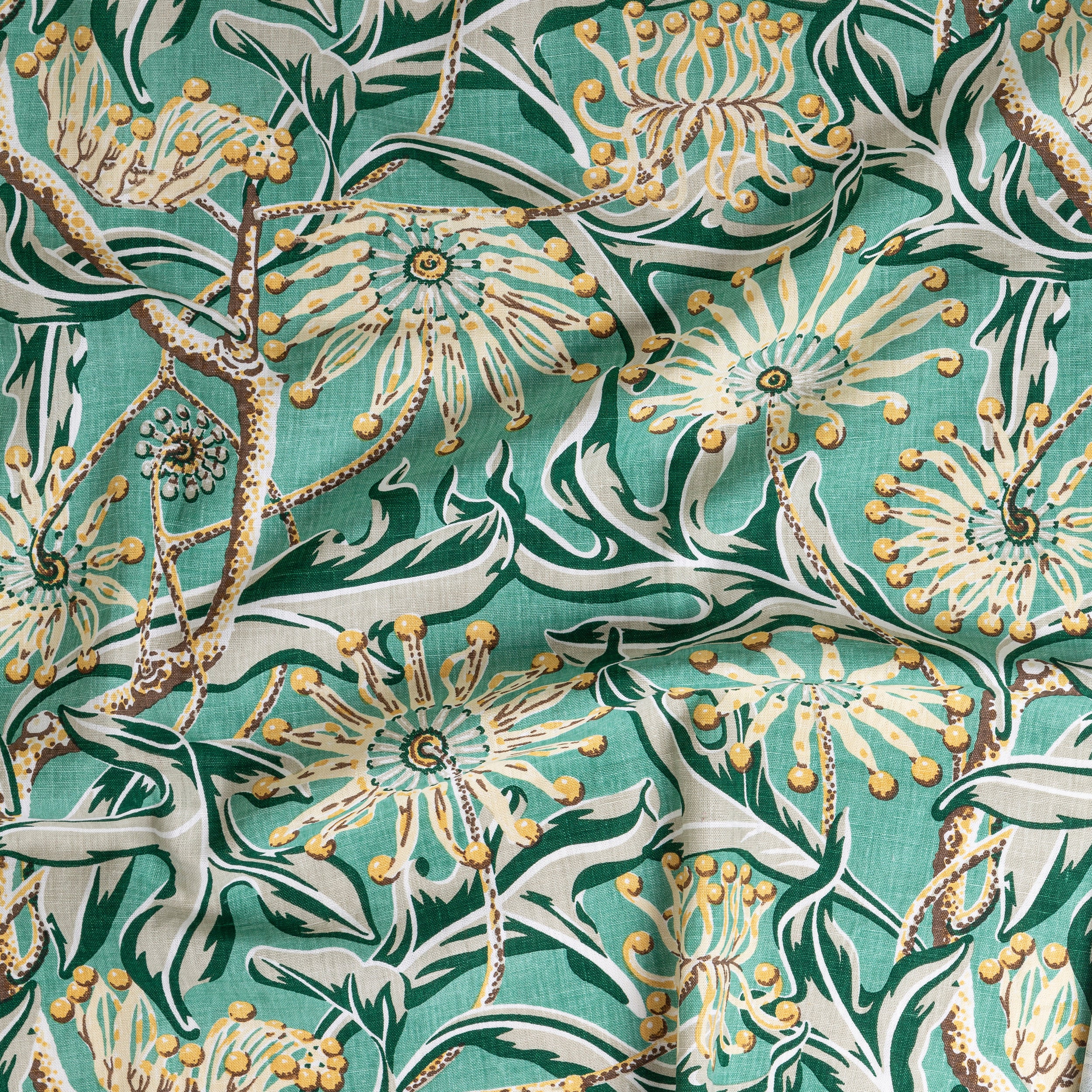 Draped fabric yardage in a large-scale floral print in green, brown and yellow on a turquoise field.