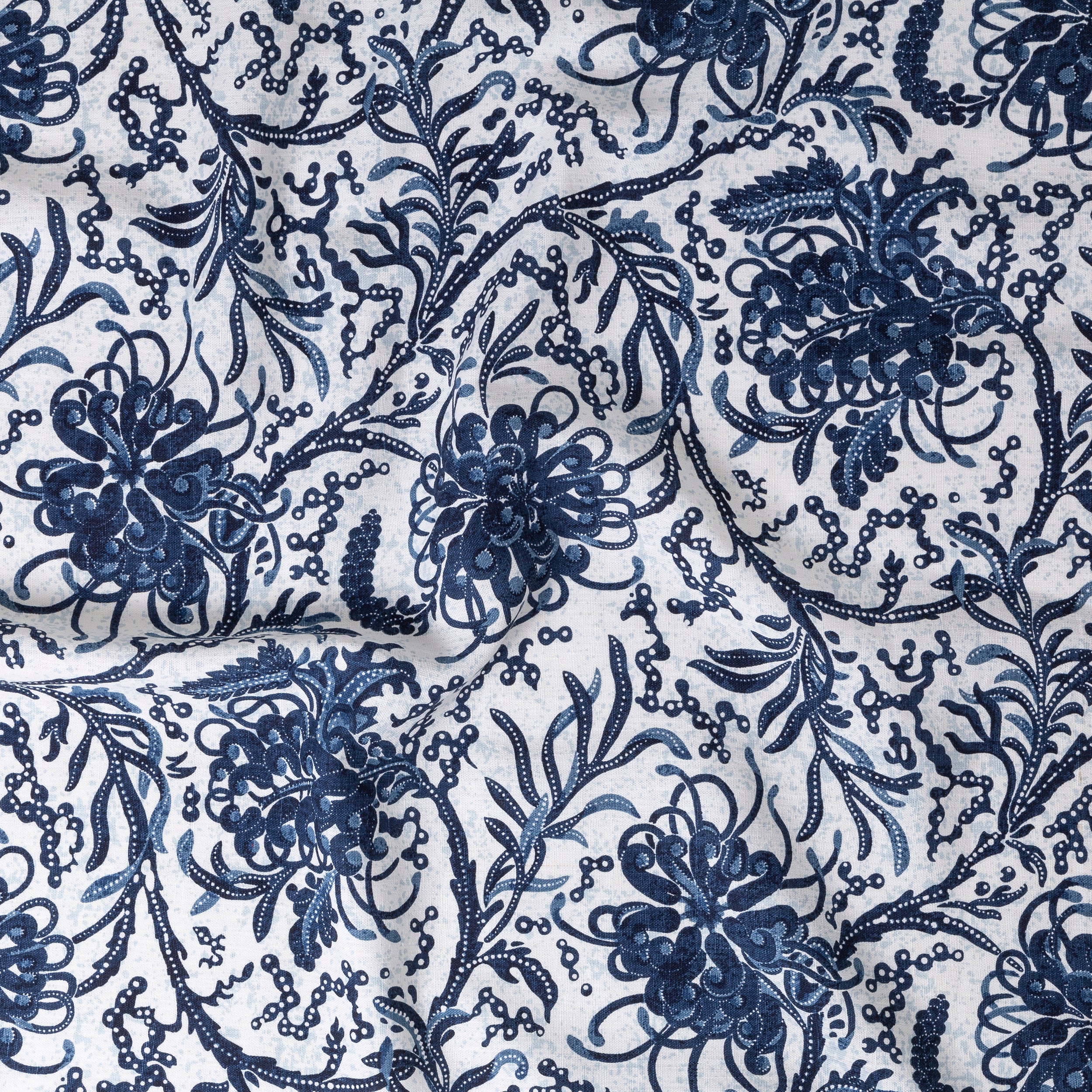 Draped fabric in a dense floral print in blue and navy on a white field.