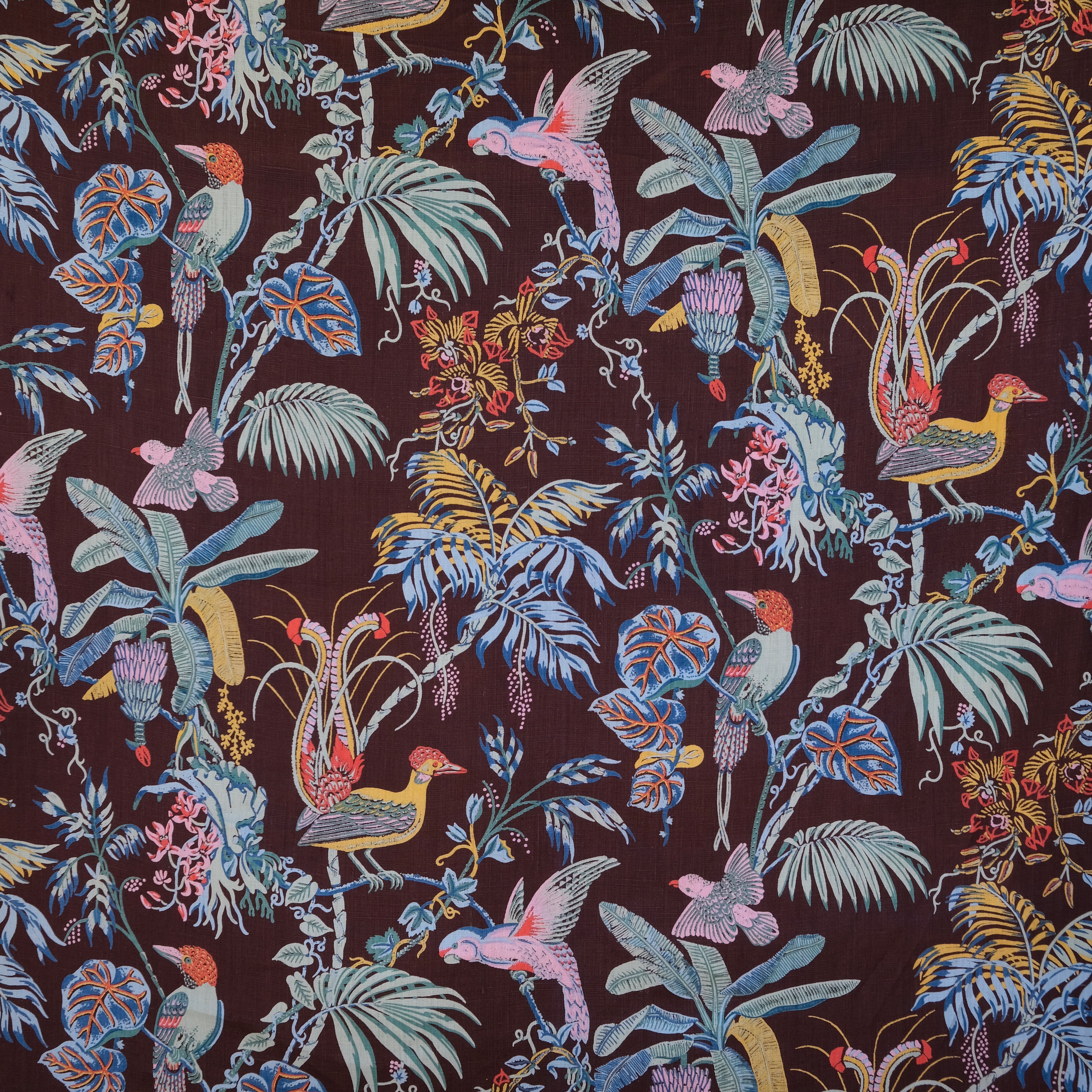 Detail of fabric in a dense leaf and bird print in a rainbow of shades on a dark brown field.