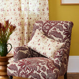 Floral-patterned armchair with a pillow against a yellow wall with a framed picture.