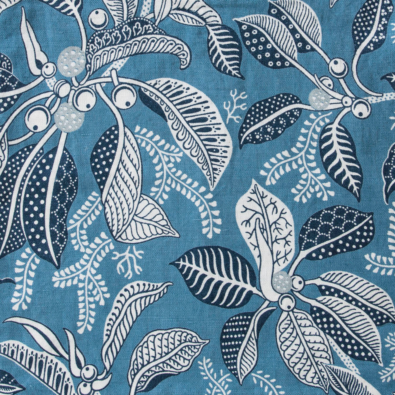 Draped fabric in a leaf and branch print in white and navy on a pacfic blue field.