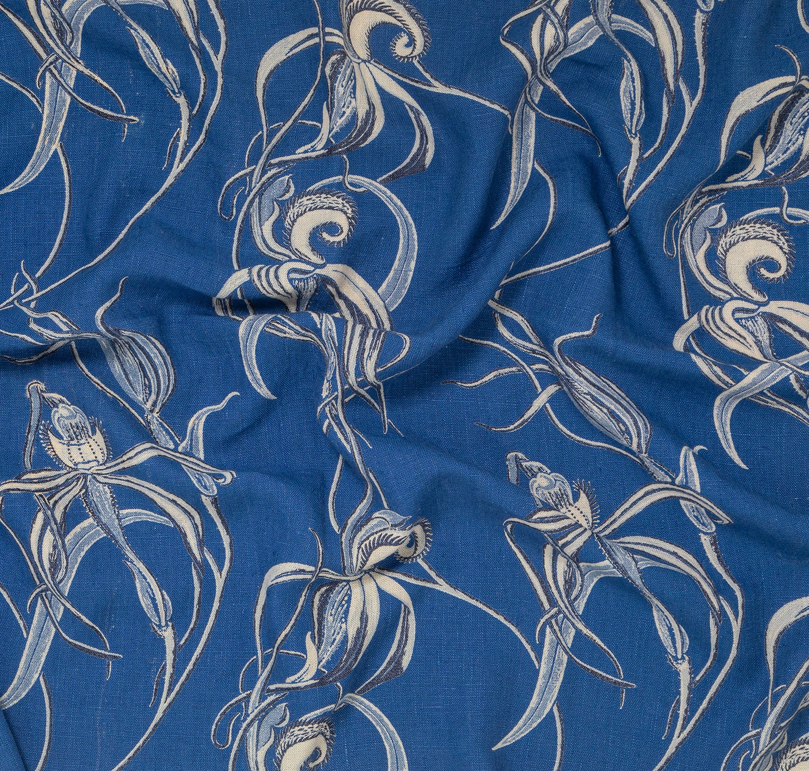 Draped fabric in a painterly orchid print in blue and yellow on a green field.