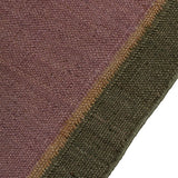 Close-up of a textured rug with a field in purple with a border of tan and green.