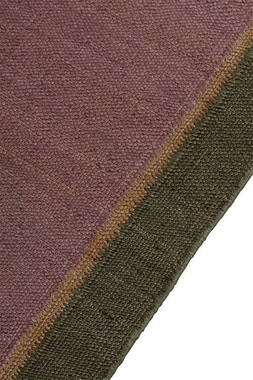 Close-up of a textured rug with a field in purple with a border of tan and green.