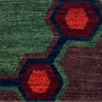Handknotted carpet close up in a geometric design in green, blue, red and purple. 