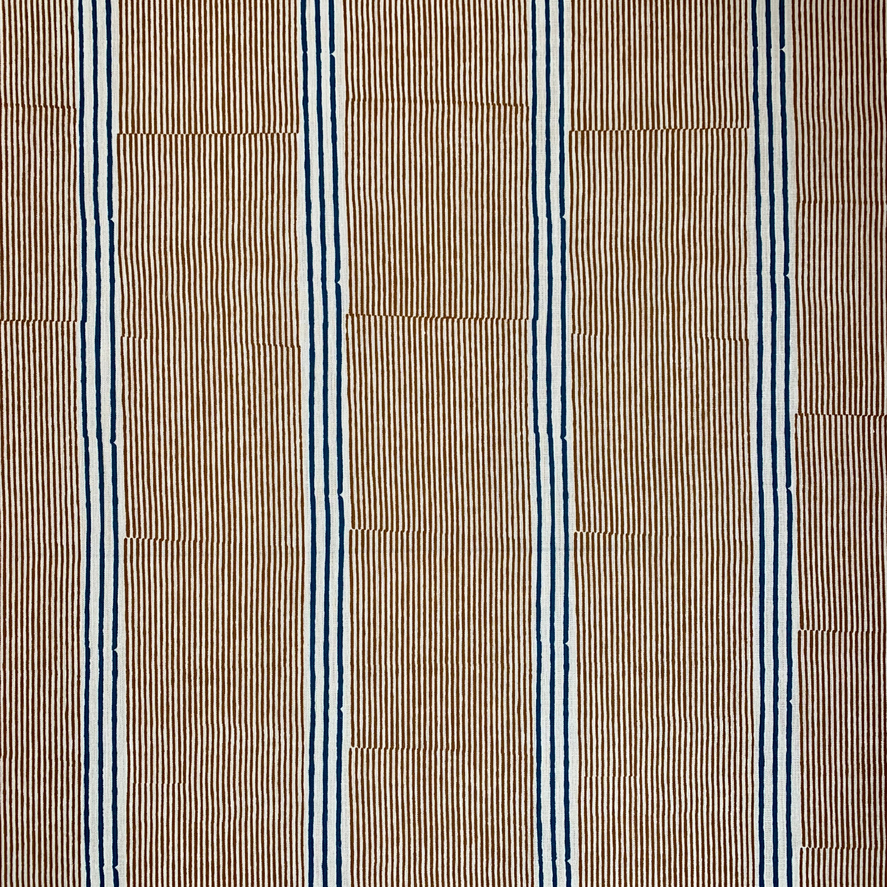 Detail of fabric in an irregular stripe print in navy and orange on a cream field.