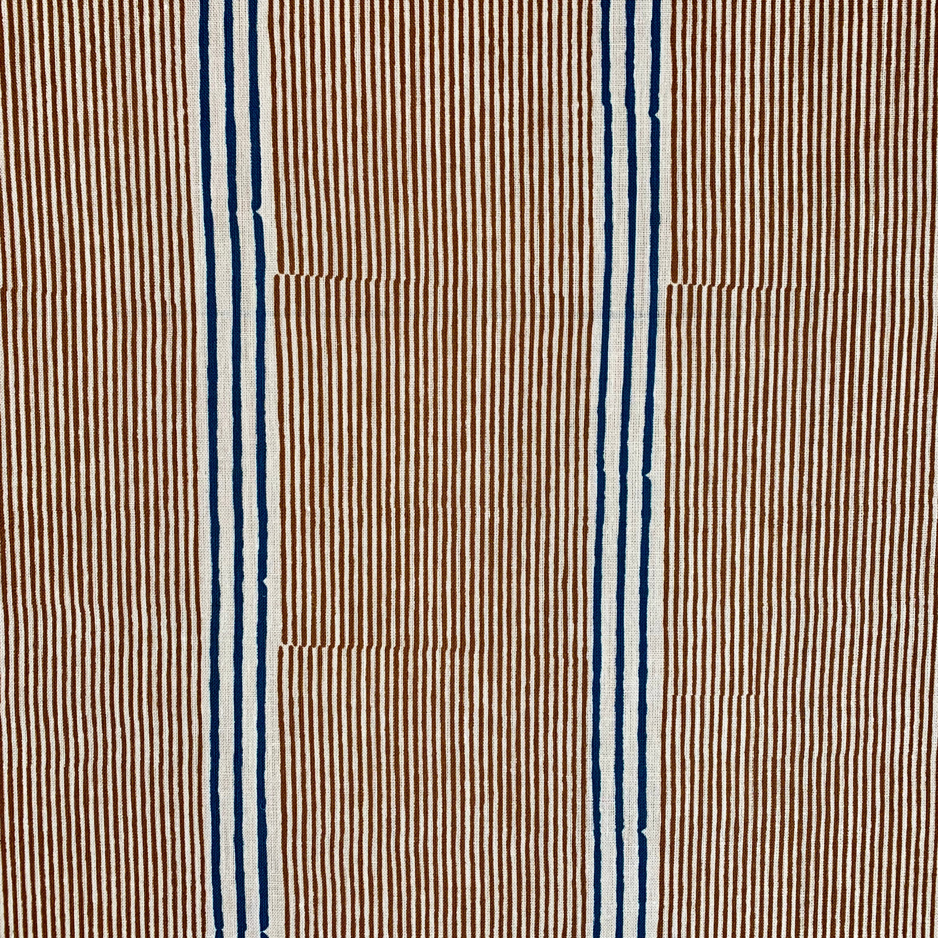 Detail of fabric in an irregular stripe print in navy and orange on a cream field.