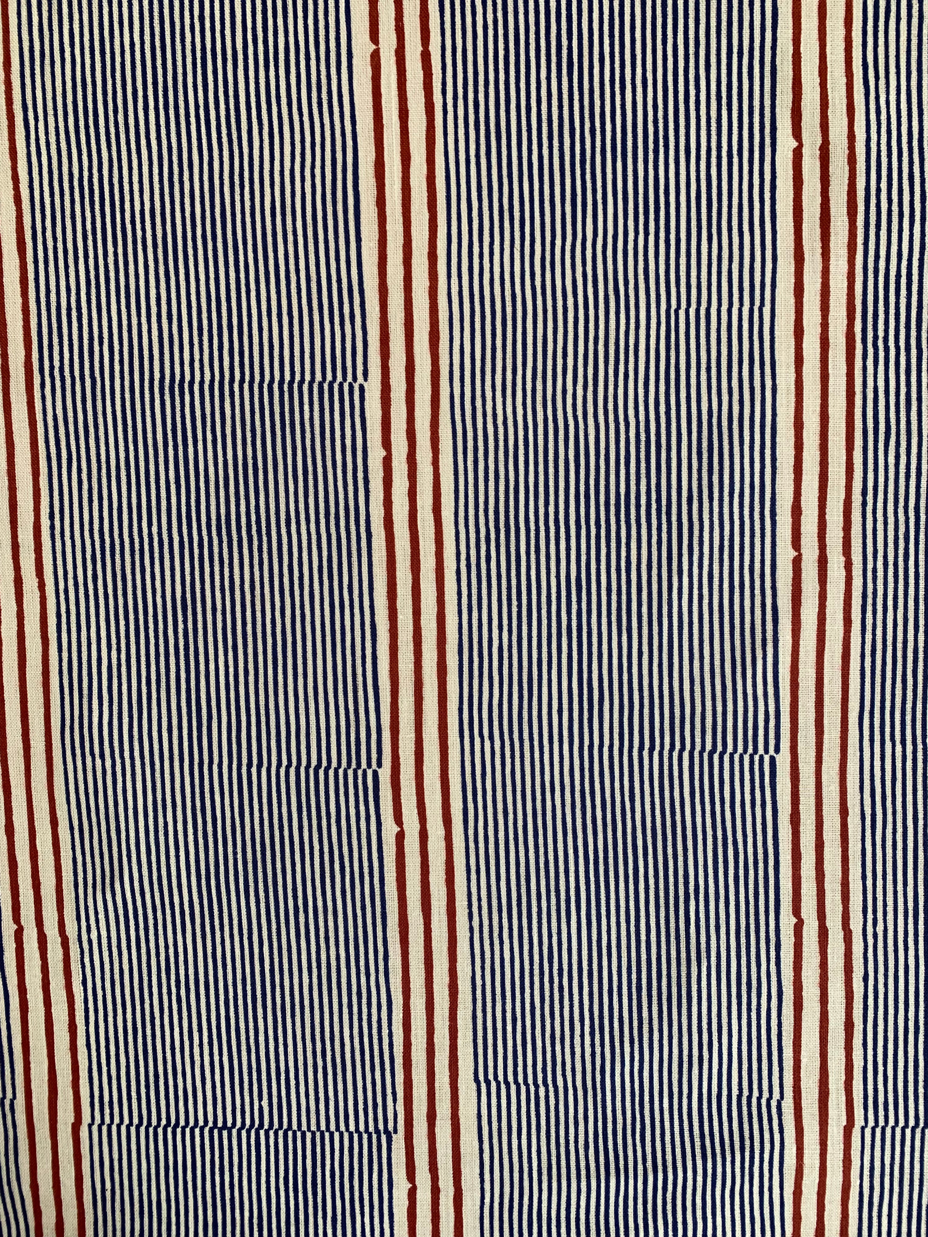 Detail of fabric in an irregular stripe print in navy and rust on a cream field.